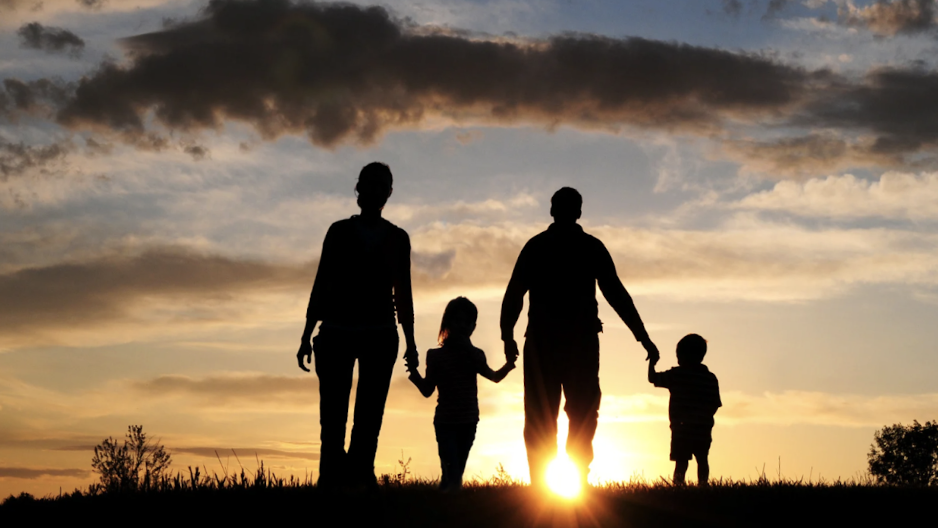 Five Money Secrets. Family walking together over a hill into a sunrise under stormy skies, symbolizing hope, unity, and a fresh start on their journey to financial security.